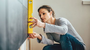 Woman using level on wall