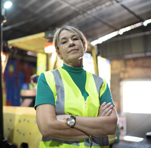 Stern female wearing yellow safety vest with arms crossed.