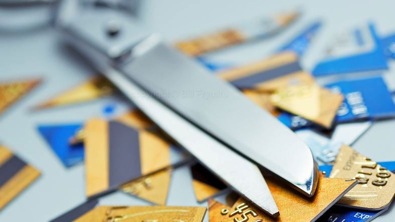 A pair of scissors on top of a pile of cut up credit cards