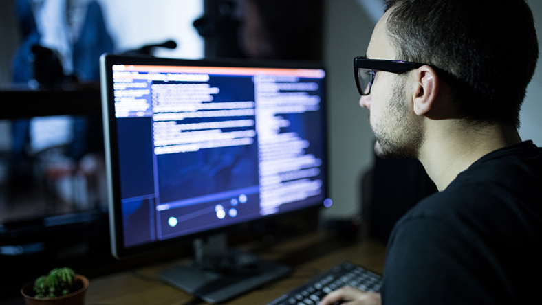 Hacker looking at stolen data on computer screen