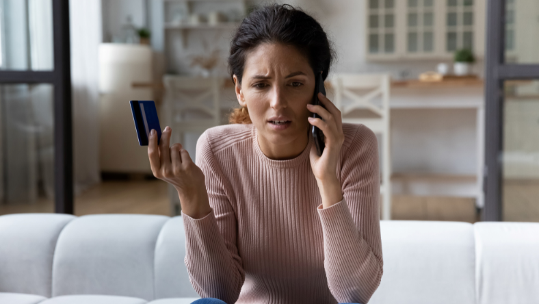 Woman holding credit card while talking on the phone