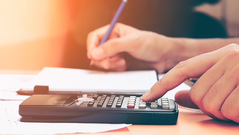 A man using a calculator and writing down some numbers