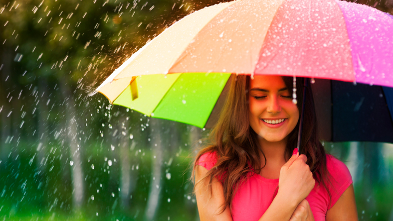 A woman standing under an umbrella as it rains