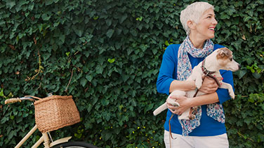 Mature woman holding dog next to bicycle