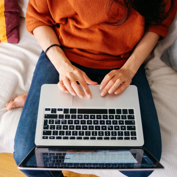 woman sitting on bed using laptop