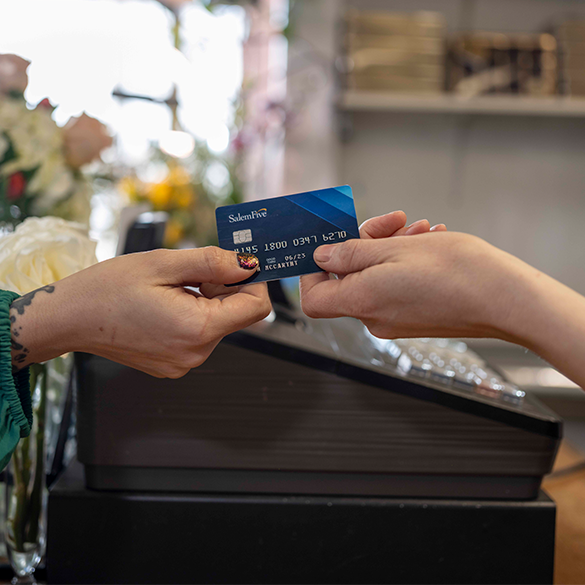 Womans hand passing Salem Five debit card to cashier