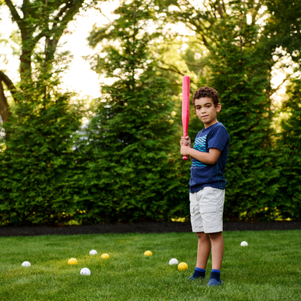 Young boy holding baseball bat in backyard
