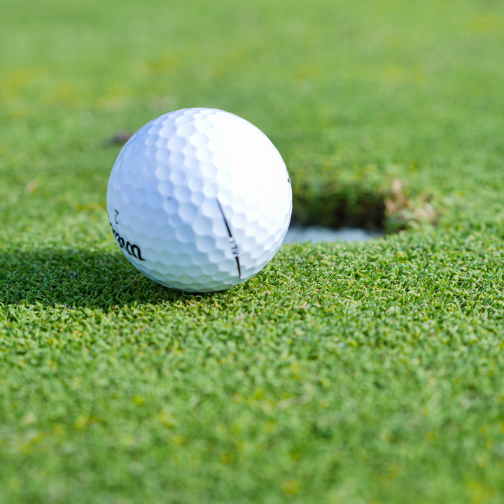 Golf ball at the edge of putting hole on green