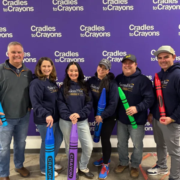 "Salem Five employees posing with oversized crayons at a Cradles to Crayons volunteer event.