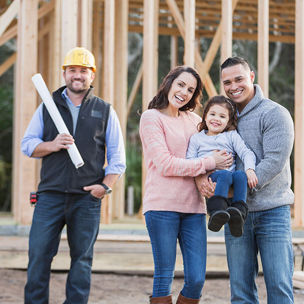 Happy family holding child standing with home construction worker.