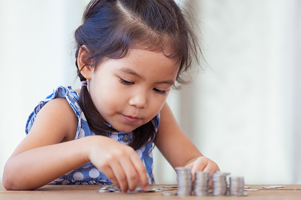 Young girl counting and stacking coins.
